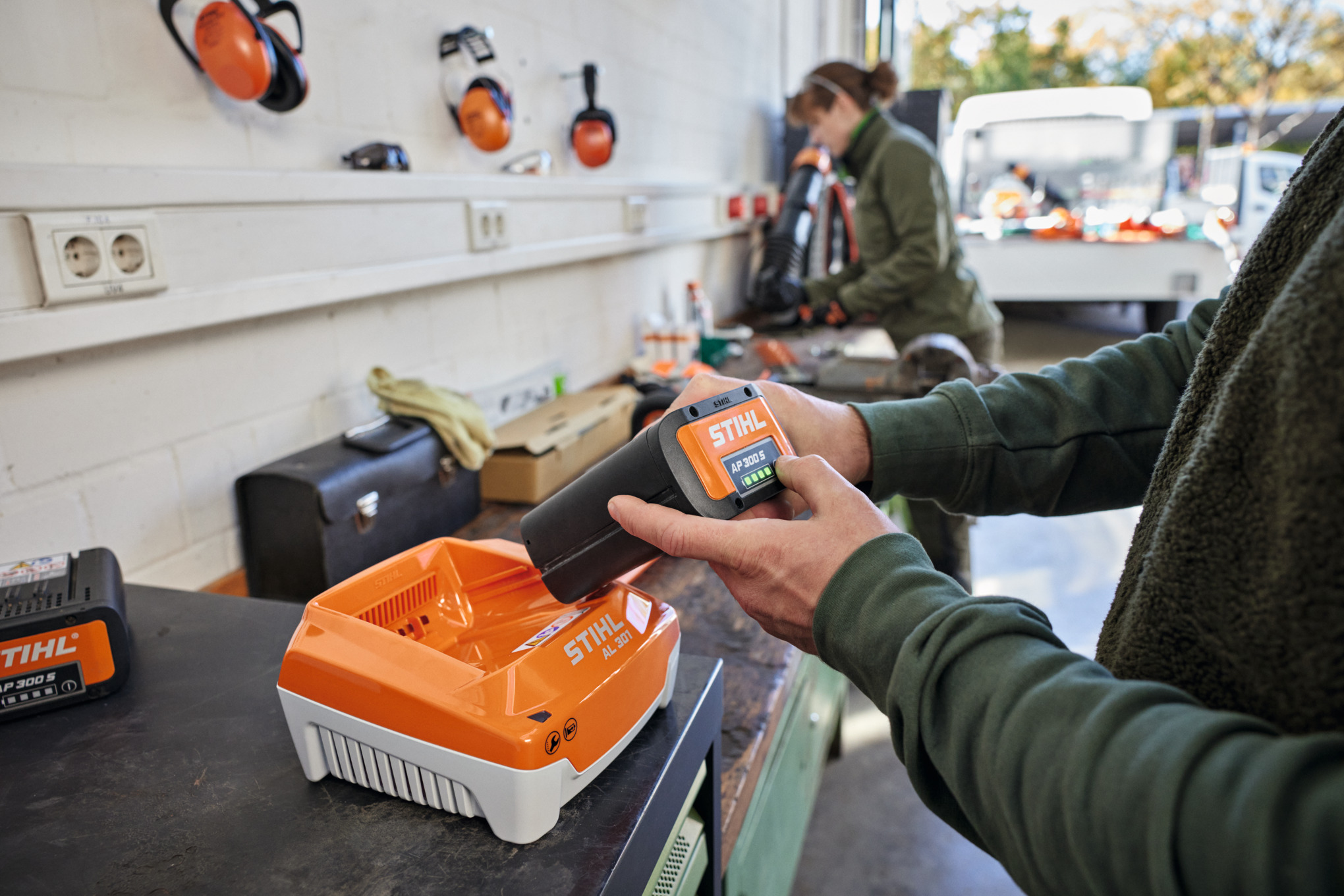 En person sætter et STIHL AP 300 S batteri i en STIHL AL 301 lynoplader