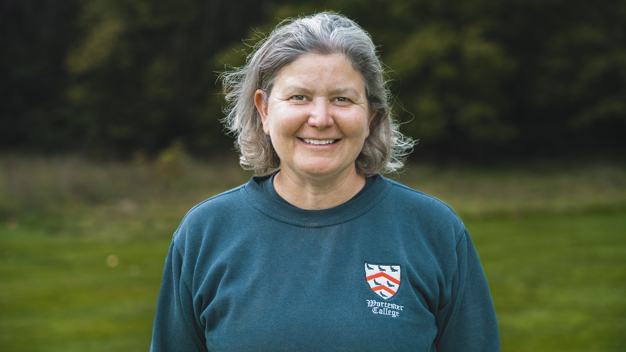 Portræt af en landskabsarkitekt fra Worcester College, der står udendørs på en græsplæne iført professionelt arbejdstøj.