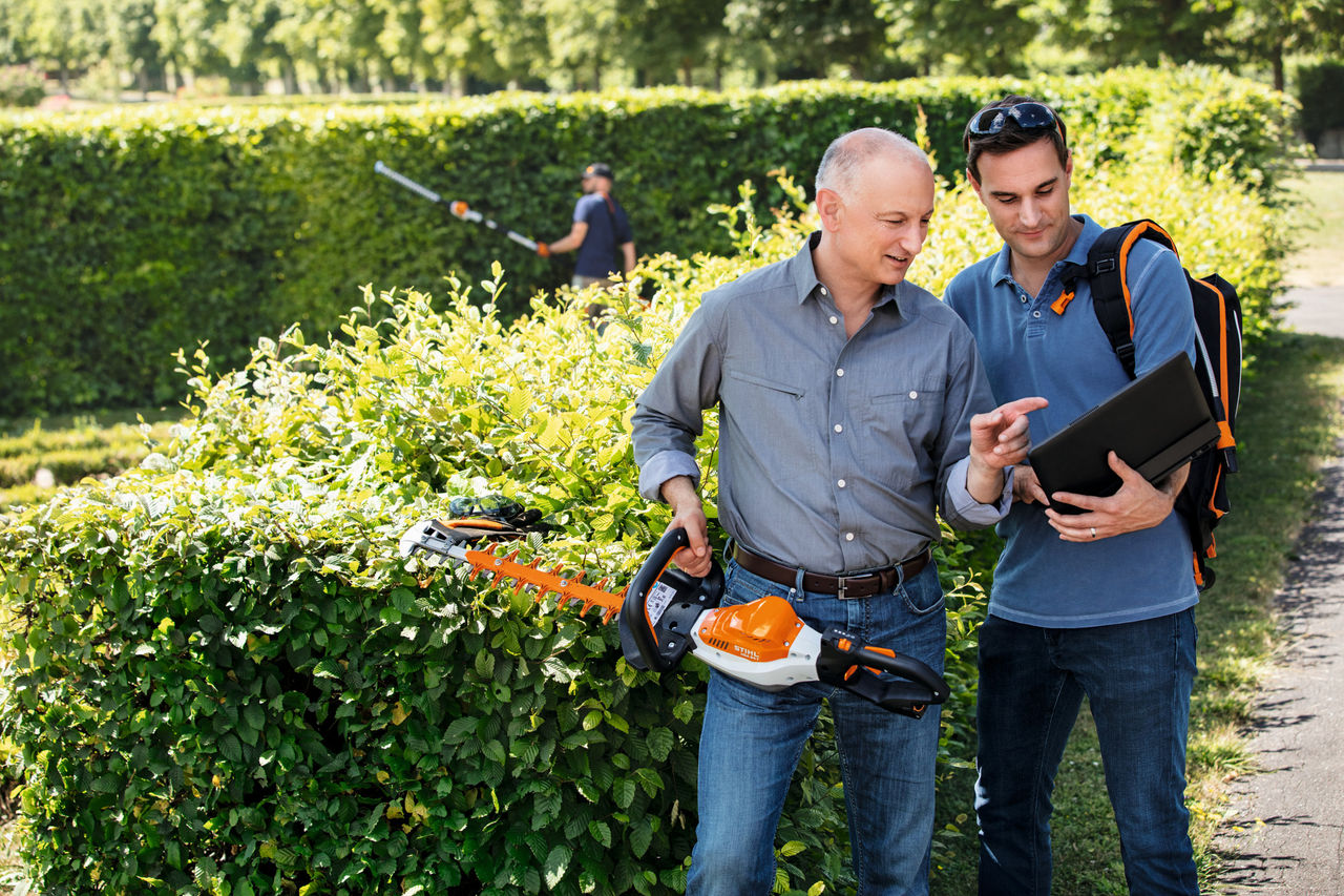 Mand med STIHL-høreværn i haven foran stablede træstammer