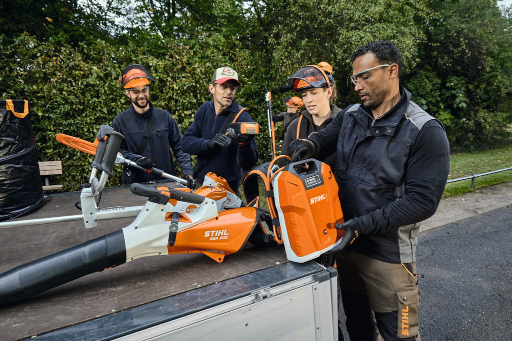 Et team af landskabsprofessionelle aflæsser deres STIHL professionelle batteridrevne udstyr fra lastområdet af et køretøj.