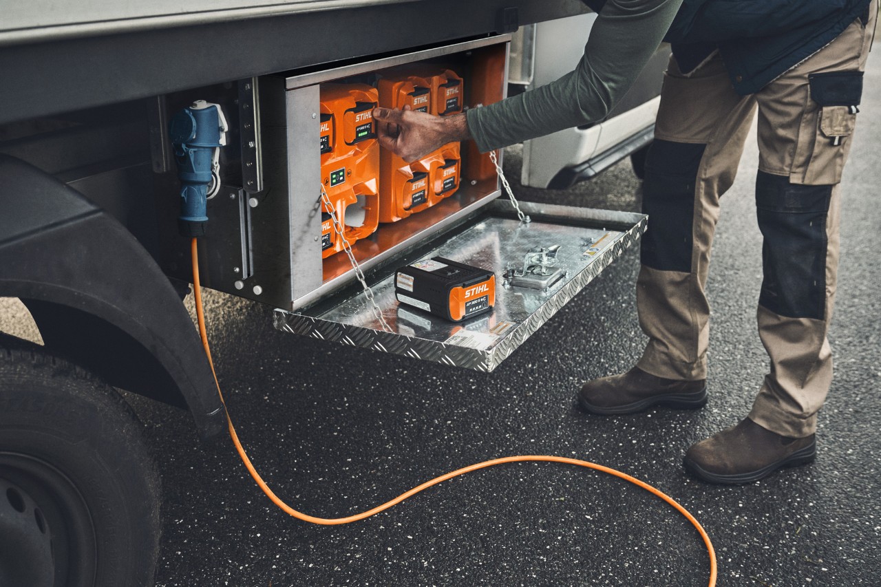 En mand tager et opladet STIHL AP 500-batteri ud af ladeboksen 
